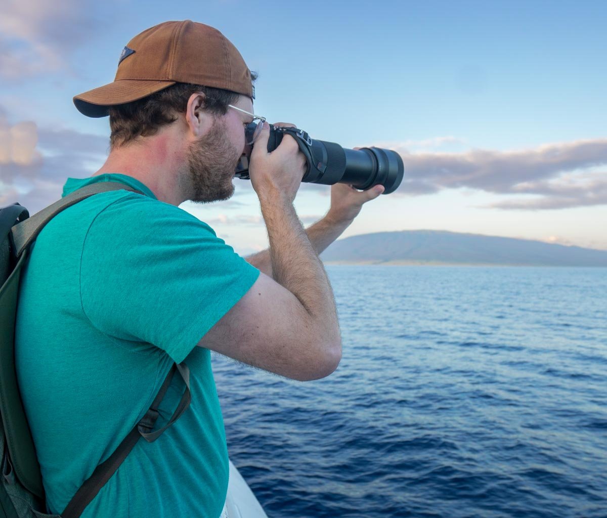 Man with a telephoto lens on a Maui whale watching tour
